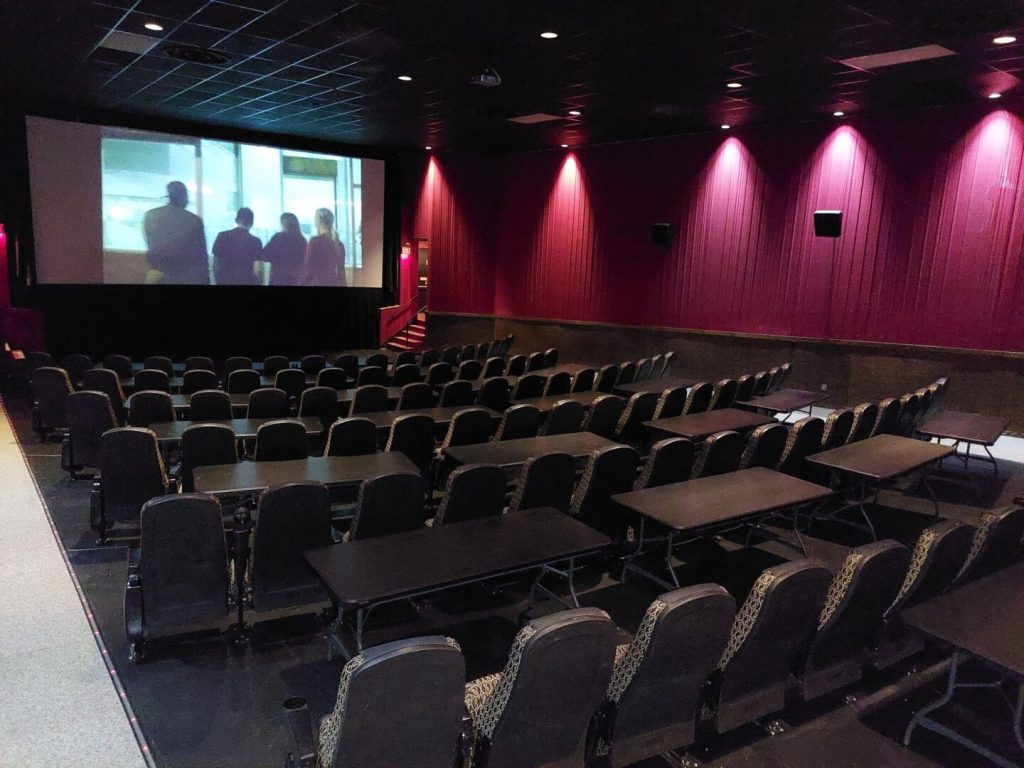 Mariner Theatre in Marinette Wisconsin. Locally Owned Movie Theater. View of the screen and the new luxury high back seats with tables in between each row. 5 feet of space between the rows